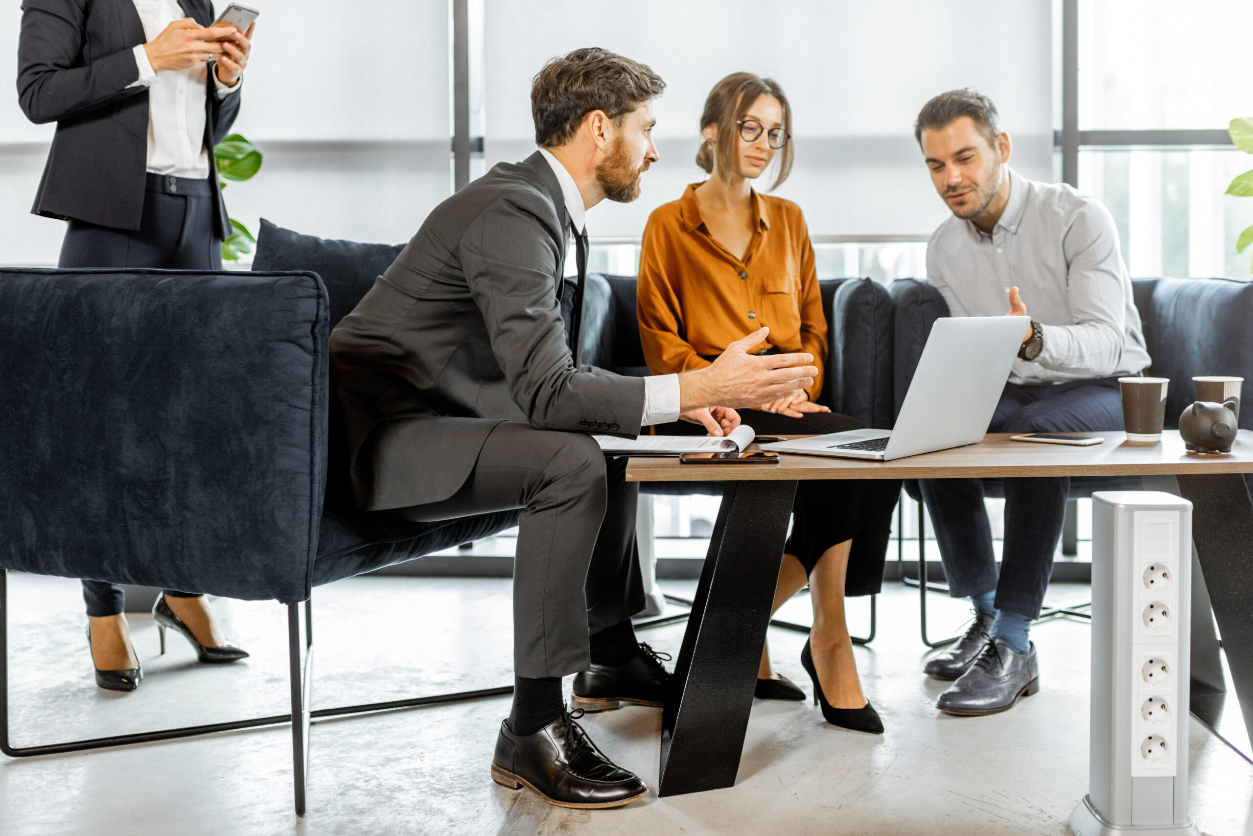 Young couple with financial advisor at the office Zwei Männer und eine Frauen in Geschäftskleidung diskutieren vor einem Laptop